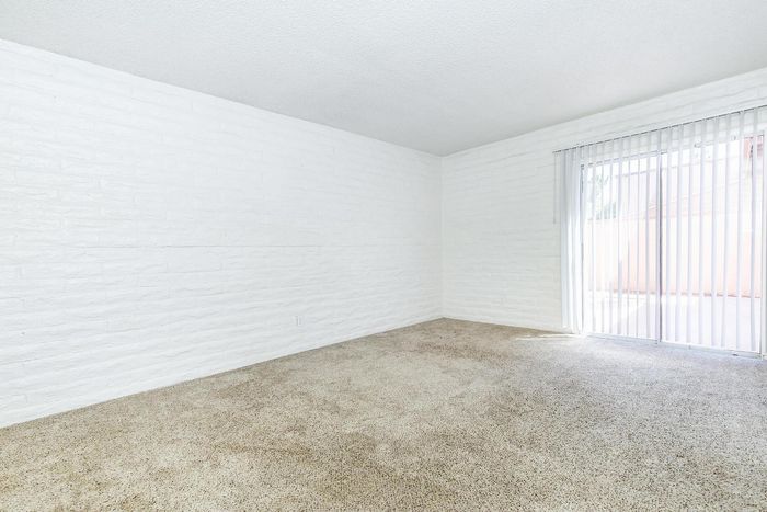 Bright and spacious room with plush carpeting and large sliding glass doors inviting natural light.