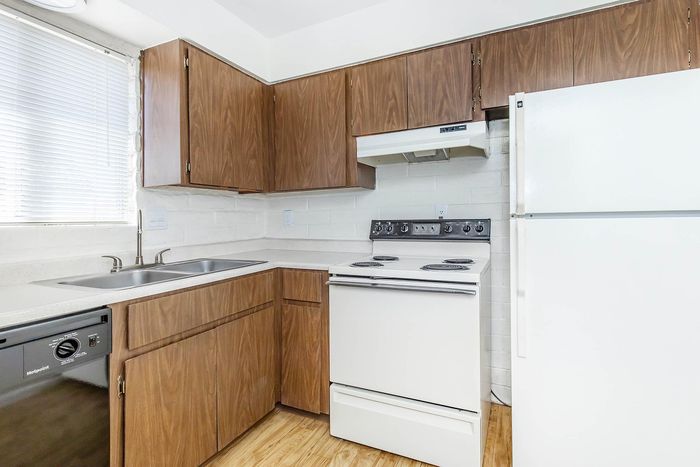 Bright kitchen with modern wooden cabinets, sleek white appliances, and a double sink.