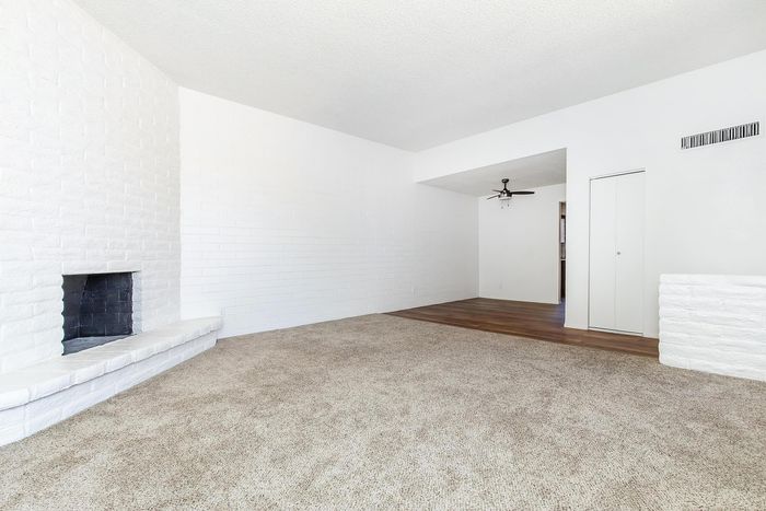 Bright living room with cozy carpeted flooring, white brick fireplace, and elegant wooden accents.