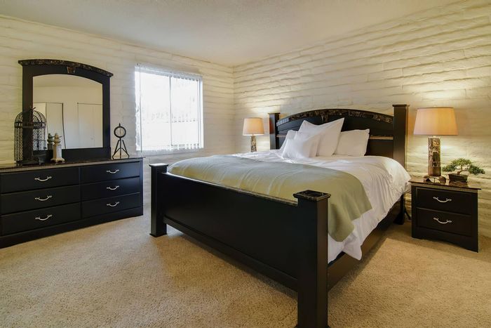 Inviting bedroom with elegant dark wood furniture, plush carpet, and ambient lighting, perfect for relaxation and comfort.