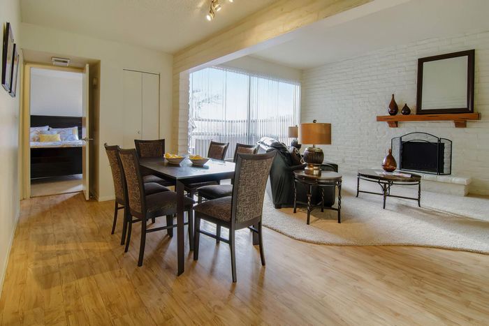 Inviting living and dining area featuring elegant furniture, large windows with abundant natural light, and a charming brick fireplace.