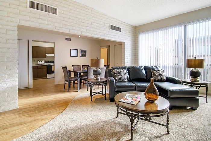 Bright and inviting living room with plush seating, elegant decor, and ample natural light flowing through large windows, seamlessly connected to a cozy dining area and modern kitchen.