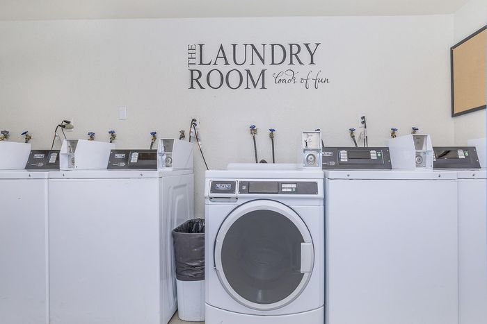 Bright and inviting laundry room with modern washers and playful wall art, promising loads of fun.