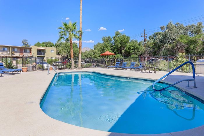 Refreshing outdoor pool with lush green surroundings and comfortable lounge chairs, perfect for relaxation and enjoyment.