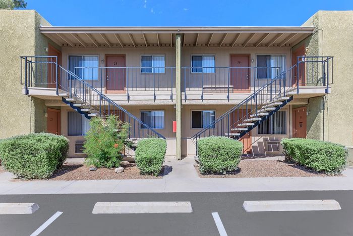 Charming two-story apartment complex with modern exterior, featuring private balconies and lush landscaping.