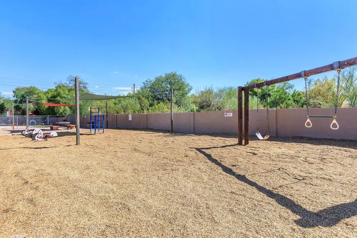 Expansive outdoor playground featuring swings, climbing frame, and picnic area under a clear blue sky.