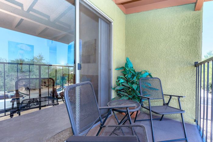 Charming balcony with stylish metal chairs and a vibrant green plant, offering a serene view for relaxation.