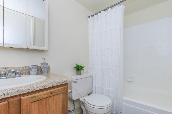 Elegant bathroom with modern fixtures, featuring a pristine countertop, sleek sink, and fresh white shower curtain for a bright, airy feel.
