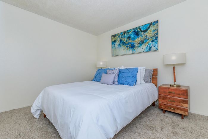 Charming bedroom with plush bedding, elegant lamps, and artful wall decor for a serene atmosphere.