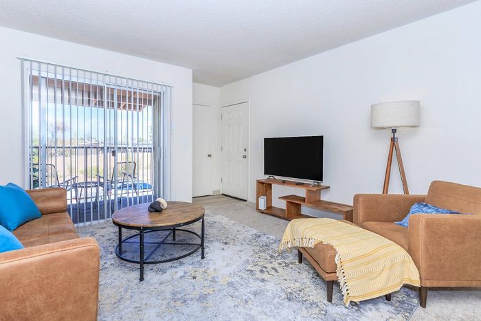 Bright and inviting living room with modern furniture, chic decor, and a view of the outdoor patio through large sliding glass doors.