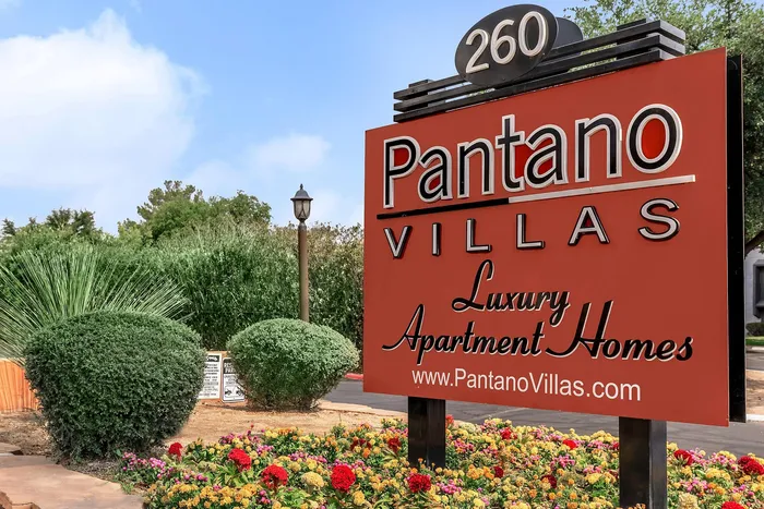 Inviting Pantano Villas entrance sign surrounded by lush greenery and vibrant flowers, showcasing luxury apartment living.