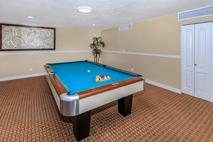 Chic and inviting game room featuring a modern pool table with vibrant felt, stylish carpeting, and contemporary wall art.