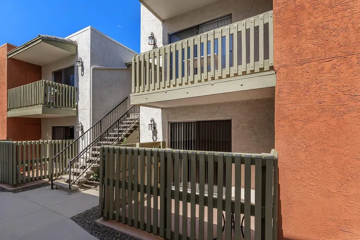 Charming apartment exterior featuring spacious balconies and a welcoming outdoor staircase against a vibrant stucco facade.