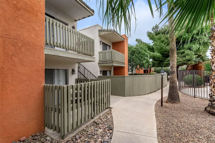 Charming apartment exterior with private balconies, set amidst lush greenery and vibrant orange accents.