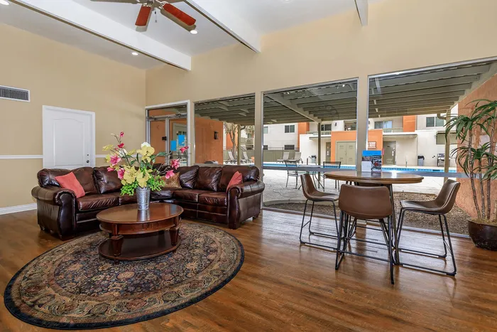 Inviting living space with plush leather sofas, elegant decor, and large windows offering a poolside view, perfect for relaxation and gatherings.