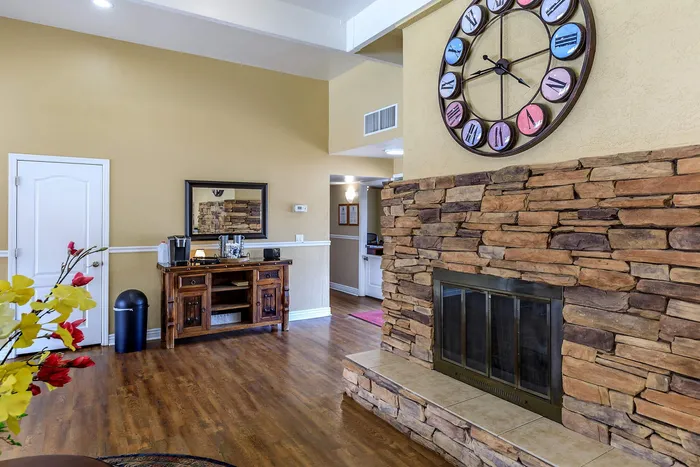 Charming living room with rustic stone fireplace, elegant hardwood floors, and a large decorative clock for a cozy ambiance.