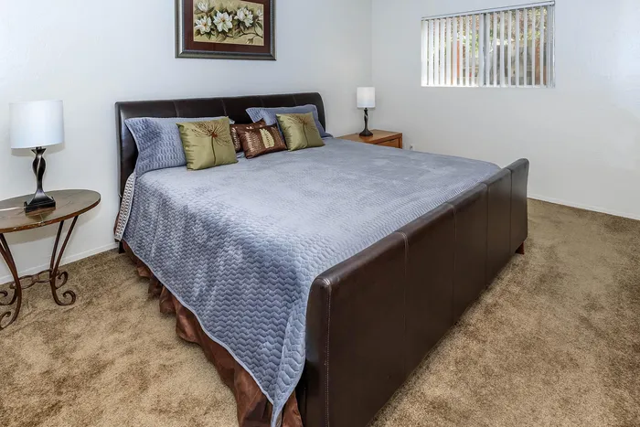 Inviting bedroom with plush king-sized bed, elegant decor, and natural light through window blinds.