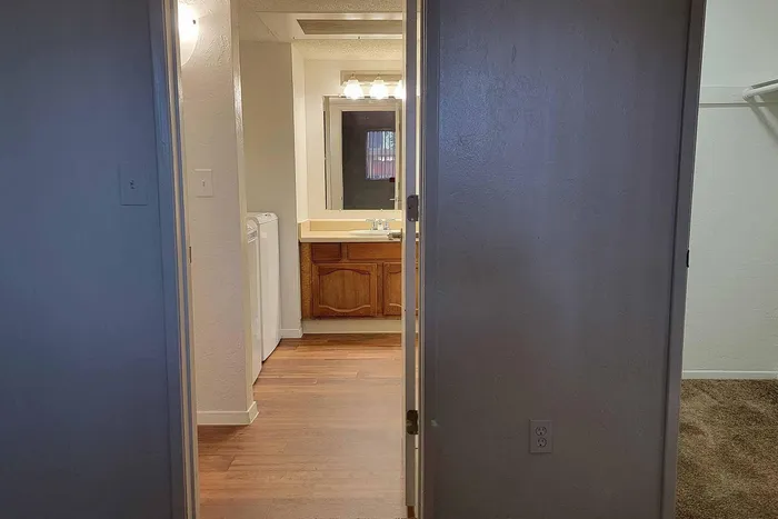 Welcoming apartment interior showcasing a well-lit bathroom with elegant fixtures and warm wooden cabinetry.