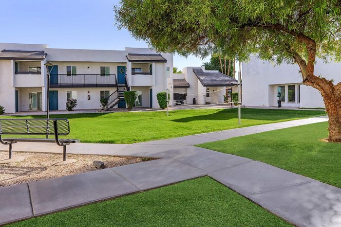 Charming apartment complex with lush green lawns, modern architecture, and serene outdoor seating.