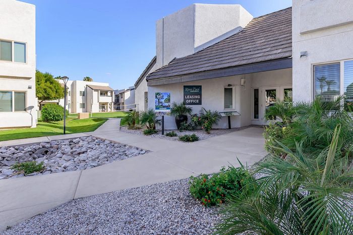 Charming apartment complex with lush landscaping and a welcoming leasing office entrance.
