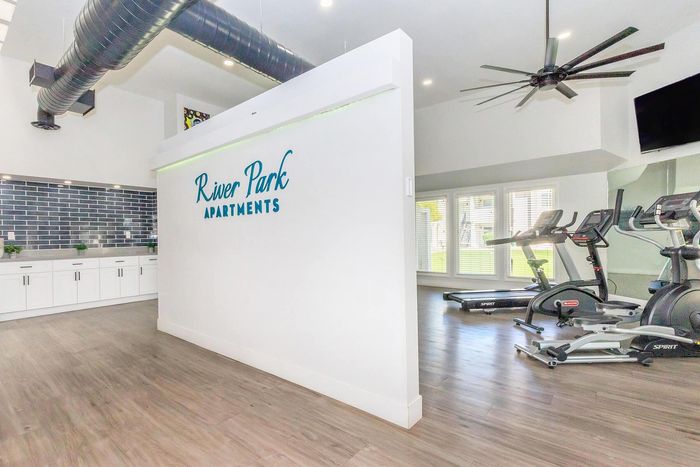 Modern River Park Apartments showcasing a stylish gym with state-of-the-art equipment and sleek kitchen design.
