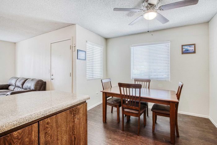 Inviting dining area with wooden table and chairs, adjacent to a cozy living room with plush seating and modern ceiling fan.