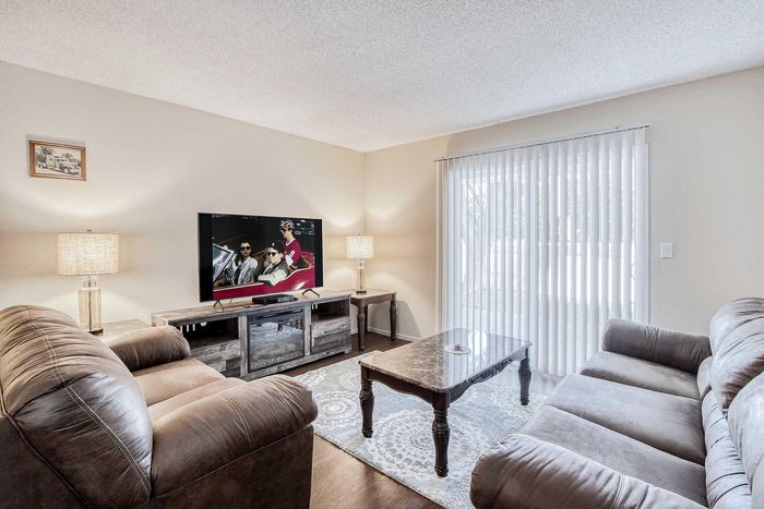 Inviting living room with plush sofas, stylish entertainment setup, and abundant natural light through sliding glass doors.