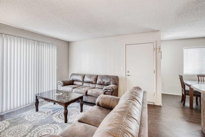 Inviting living room with plush sofas, a chic coffee table, and elegant wood flooring, effortlessly connecting to a bright dining area.