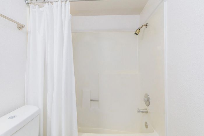 Bright and modern bathroom with a sleek, white shower and crisp shower curtain, offering a refreshing and inviting space.