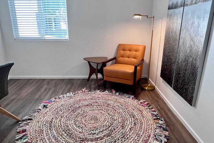 Cozy reading nook featuring a stylish orange armchair, chic side table, and a patterned round rug under soft lighting.