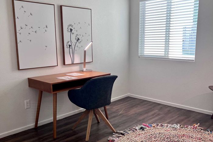 Bright and inviting home office space with a sleek wooden desk, stylish swivel chair, and elegant dandelion artwork, perfect for productivity and creativity.