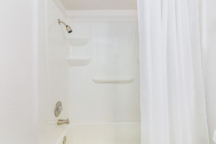 Elegant modern bathroom featuring a pristine white shower with sleek fixtures and a clean shower curtain.