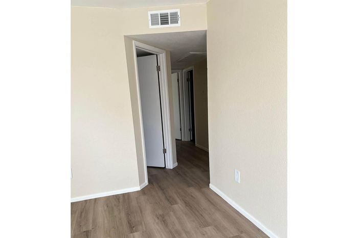 Inviting hallway with elegant wood flooring and soft neutral walls, leading to multiple rooms for versatile living.