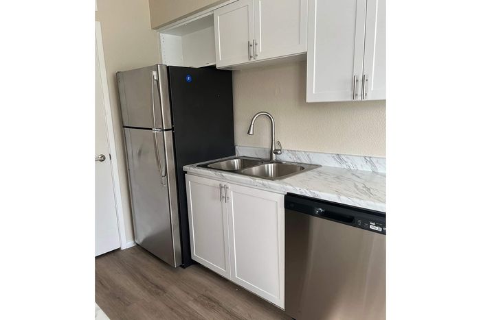 Modern kitchen featuring sleek stainless steel appliances, elegant marble countertops, and pristine white cabinetry.