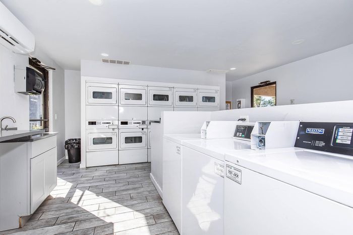 Modern laundry room with multiple high-efficiency washers and dryers, sleek countertops, and abundant natural light.