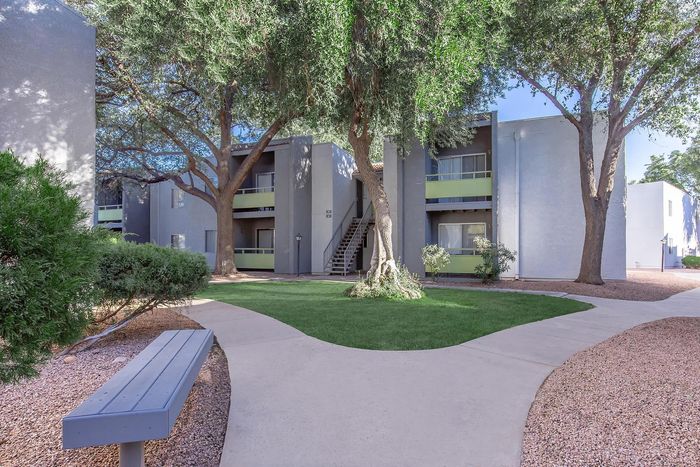 Charming apartment complex with lush greenery, scenic pathways, and inviting outdoor seating.