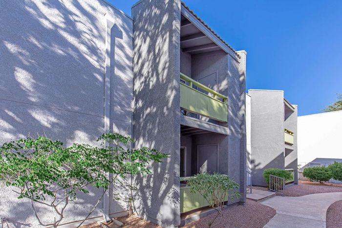 Charming and modern apartment exterior with sleek architectural design and vibrant greenery under a clear blue sky.