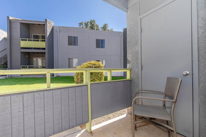 Charming apartment balcony offering a cozy outdoor space with green views and stylish seating.