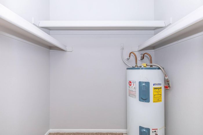 Inviting storage area featuring ample shelving and a modern water heater, perfect for organization.