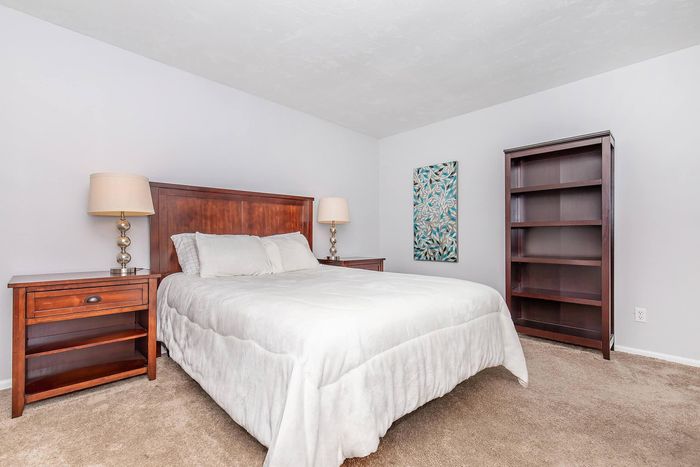 Cozy bedroom with a luxurious wooden bed, elegant nightstands, and soft carpeting, creating a warm and inviting atmosphere.