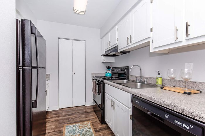 Modern kitchen with sleek white cabinetry, stainless steel appliances, and elegant countertops complementing a stylish wood floor.