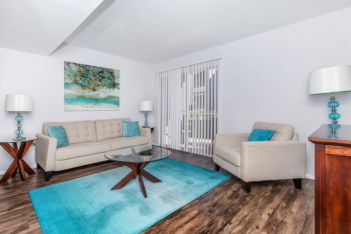 Bright and inviting living room featuring elegant beige seating, vibrant teal accents, and contemporary decor, perfect for relaxation.