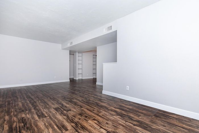Bright open-concept living space featuring elegant wood flooring and built-in shelving, perfect for modern living.