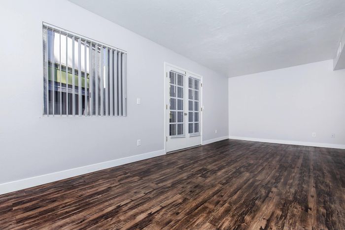 Bright and inviting living space with elegant hardwood flooring, large window, and stylish French doors.