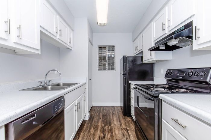 Modern kitchen with sleek white cabinetry, stainless steel appliances, and elegant hardwood flooring, offering a bright and functional space for cooking.