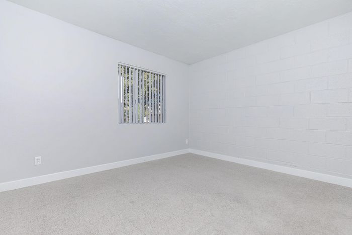 Bright and spacious bedroom with neutral carpeting and large window for natural light.