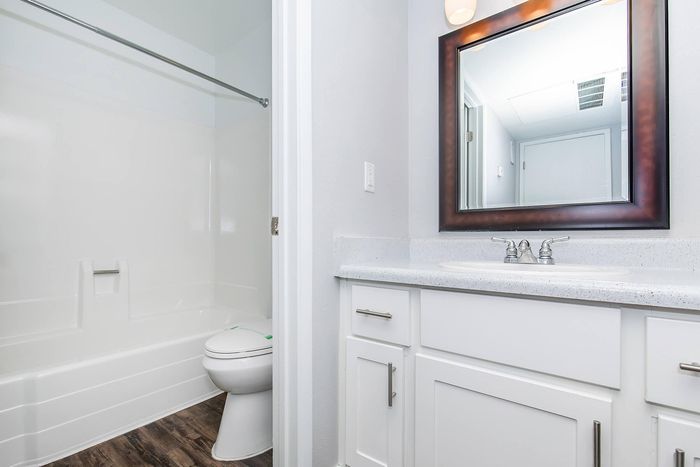 Bright and modern bathroom with stylish white cabinetry, elegant countertop, and framed mirror above a sleek sink.