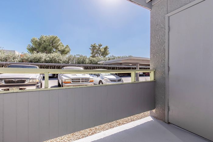 Bright outdoor patio view with adjacent parking area and lush greenery, showcasing a welcoming and convenient apartment setting.