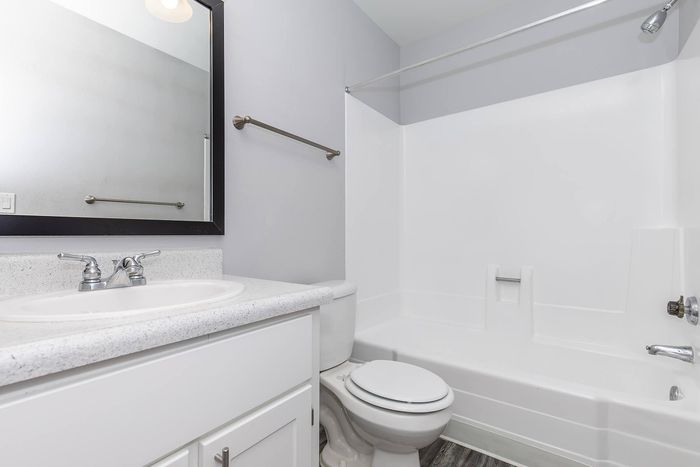 Sleek and modern bathroom featuring a pristine bathtub, elegant sink with polished fixtures, and a large mirror in a bright, inviting space.