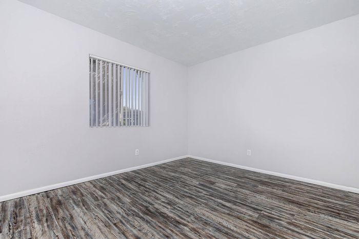 Bright and airy room with sleek wood flooring and a large window for natural light.